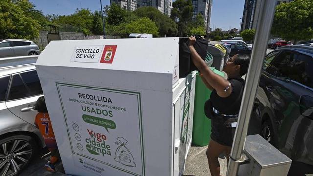 Una mujer depositando prendas en un contenedor de ropa y calzado de Vigo.