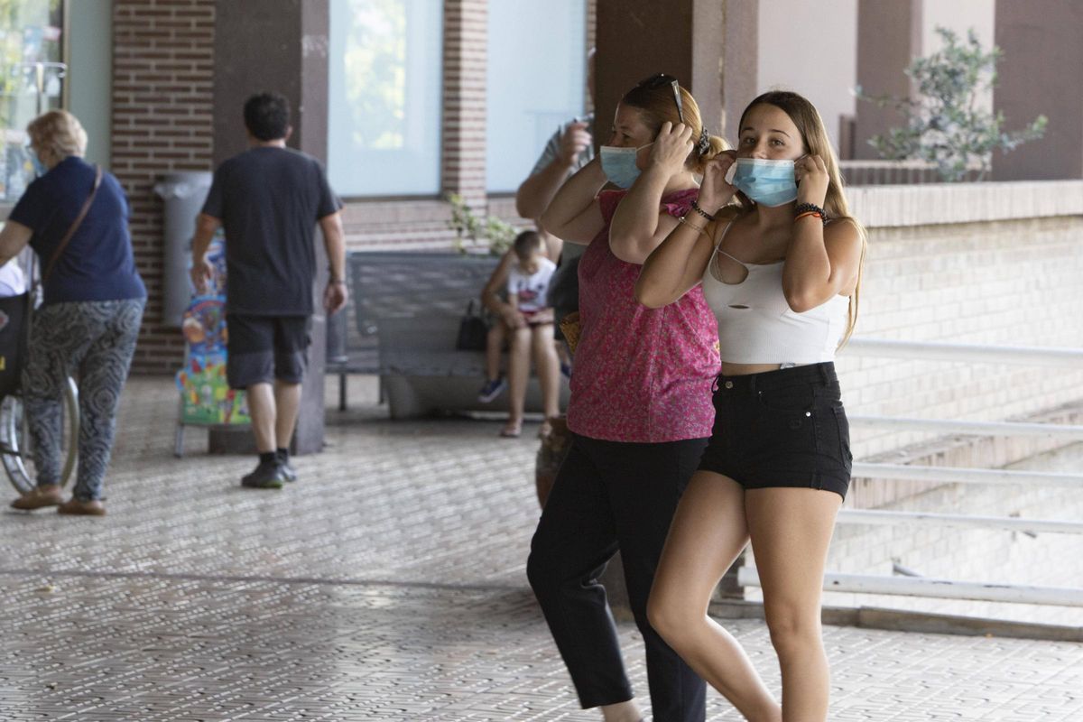 Dos mujeres poniéndose la mascarilla al entrar al hospital de Xàtiva.