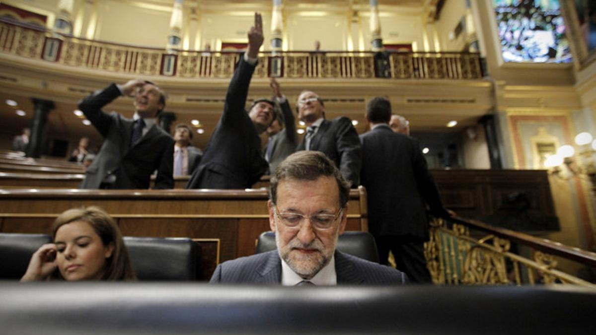 Mariano Rajoy, en su escaño, mientras, detrás, varios diputados observan la gotera del Congreso.