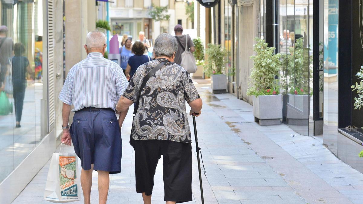 Una pareja de personas mayores paseando por una calle de la provincia de Alicante