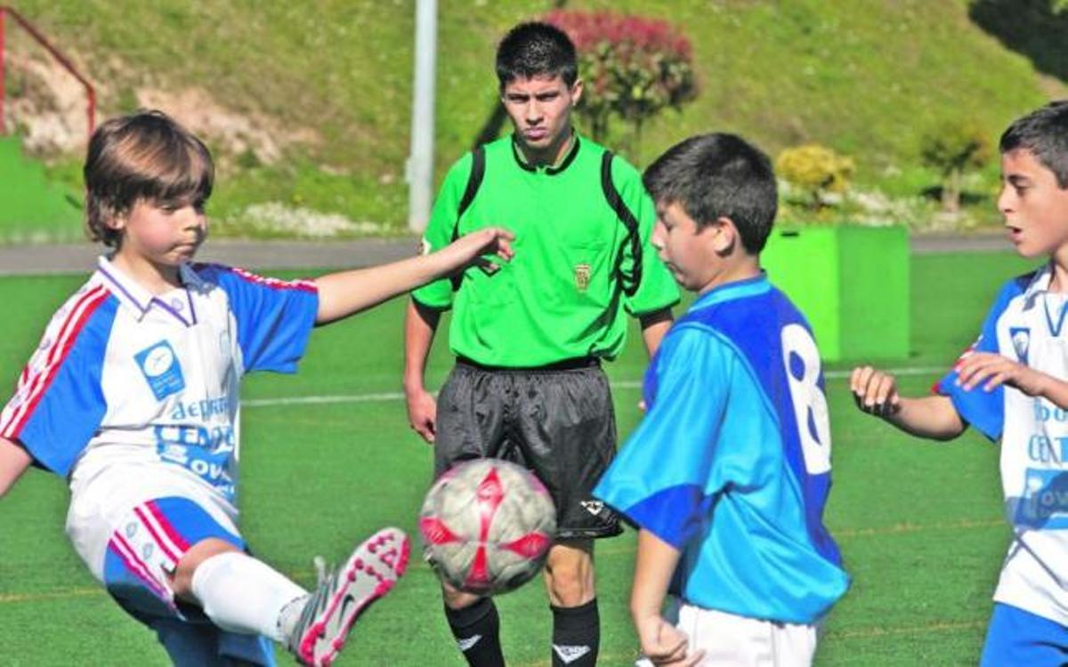 El árbitro Kevin Ortega dirige un partido de alevines en el campo del Cristo. En la fotografía de la derecha, Edwin Salas (a la derecha de la imagen, dándole la mano a un jugador del Astur) se dispone a hacer de asistente en un partido de juveniles entre el Arenal y el Astur, en el Hermanos Llana. / Irma Collín