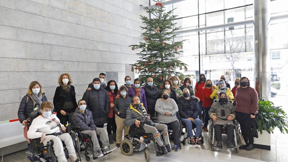 Usuaris de les entitats del Tercer Sector davant l&#039;arbre de Nadal a la delegació de la Generalitat.