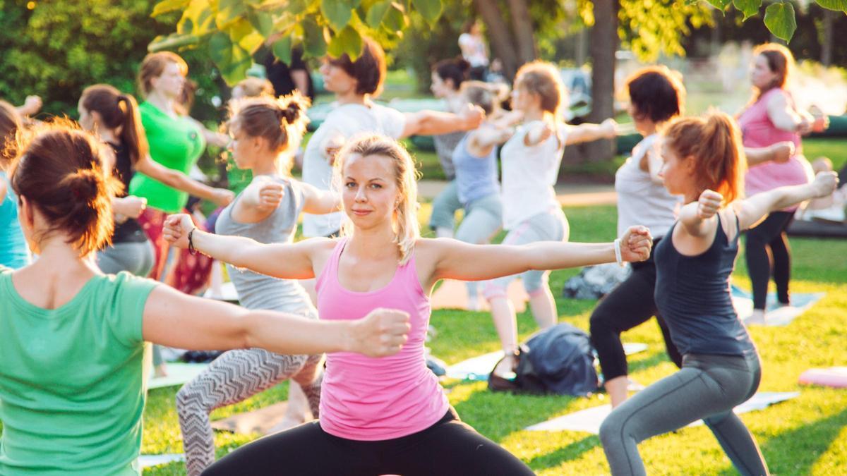 A group of people doing yoga in a park.