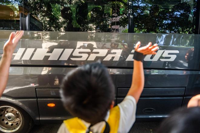Un niño despide a un autocar que se marcha de colonias, este verano.