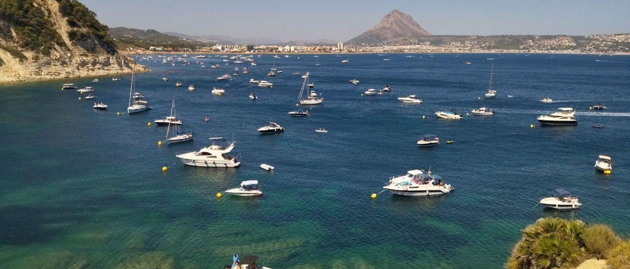 La cala Sardinera, de Xàbia, llena de barcos fondeados en una zona con posidonia.