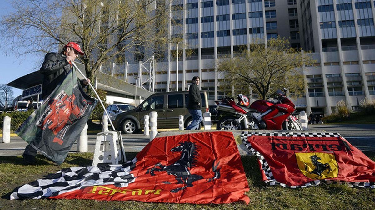 Un seguidor de Michael Schumacher col·loca diverses banderes de Ferrari als voltants l’hospital de Grenoble on està ingressat l’expilot de F-1