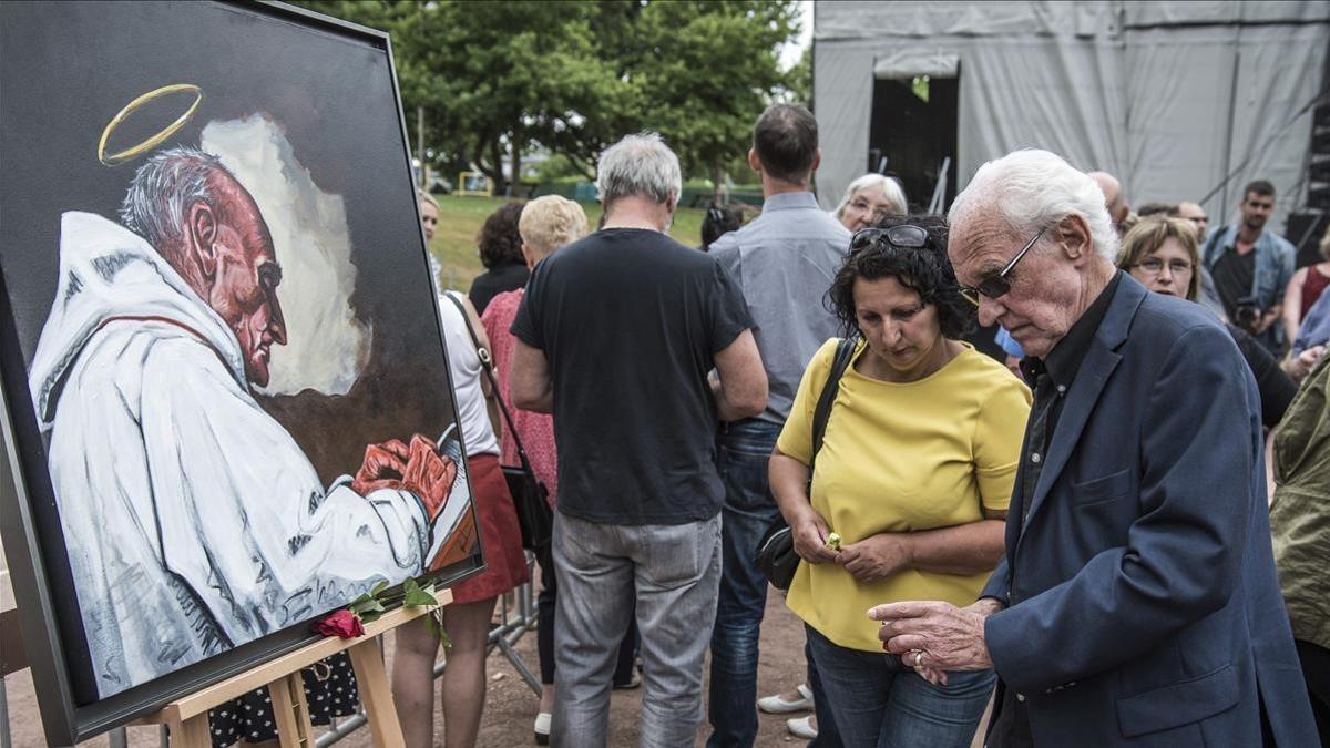 Varios ciudadanos encienden velas delante de un retrato del cura Jacques Hamel, asesinado en un atentado yihadista  en Saint Etienne du Rouvray, en Francia.
