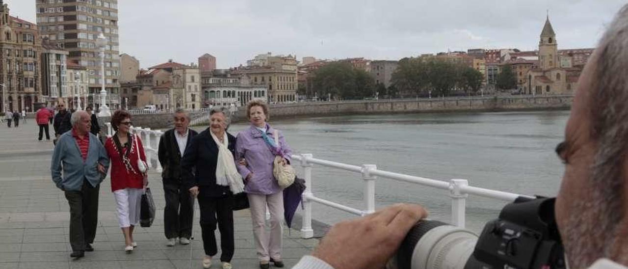 Personas mayores pasean por el Muro de Gijón.