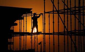 Es fa de dia mentre un treballador instal·la una bastida en una obra de construcció del tren d’alta velocitat al viaducte de Hefei (Xina).