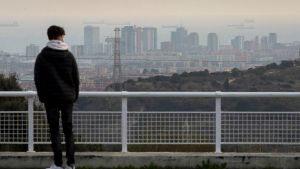 Un joven observa el paisaje de Barcelona en un episodio de alta contaminación por partículas PM10, en una imagen de archivo. EFE/ Enric Fontcuberta.