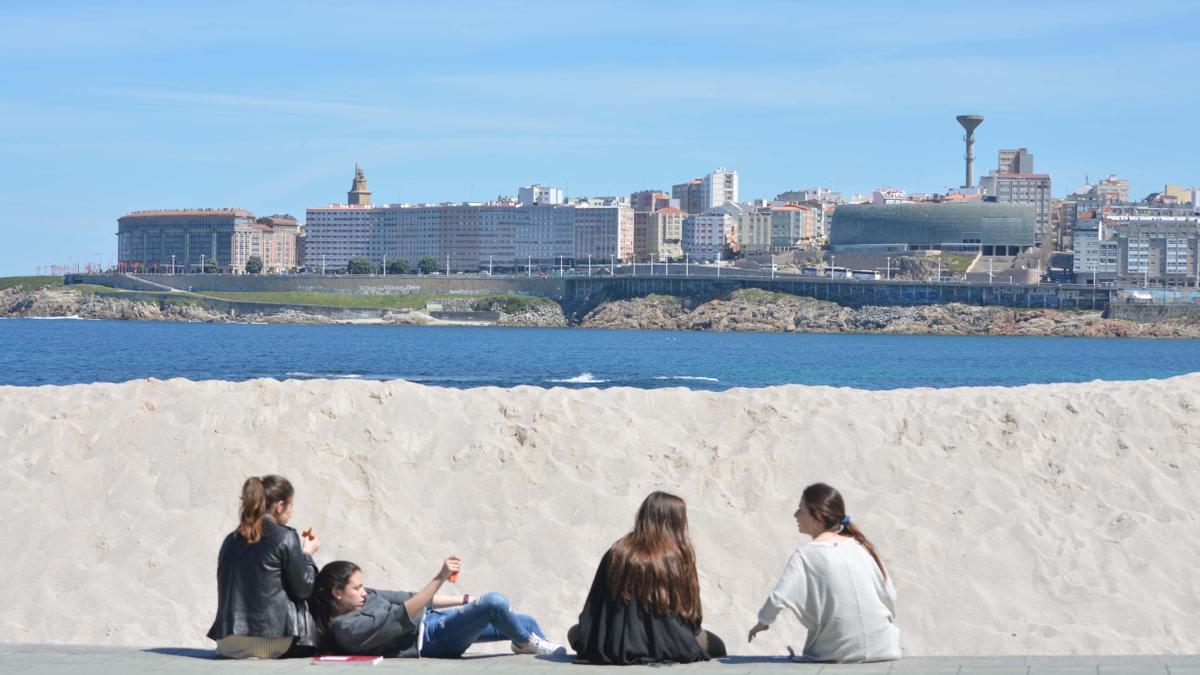 Un grupo de jóvenes en el paseo marítimo de A Coruña un día soleado de invierno.