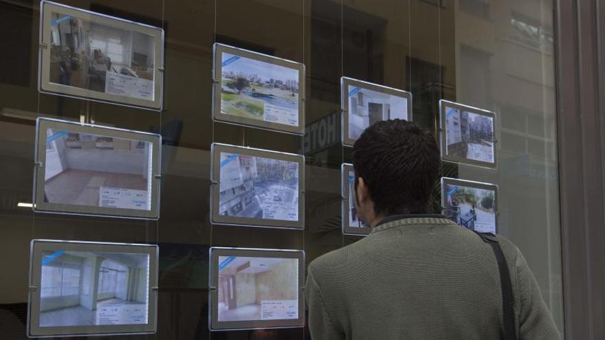 Un joven mirando un escaparate de una inmobiliaria