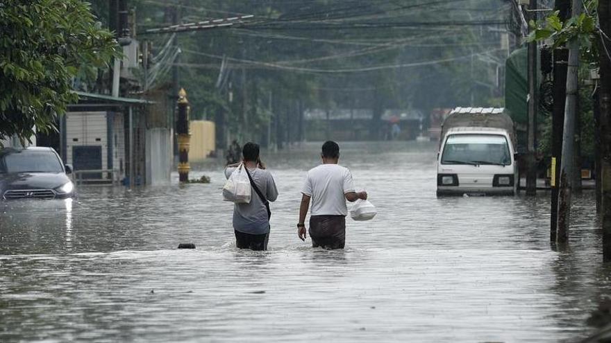 Dos personas caminan en una calle inundada tras una tormenta extrema en Bago, en Myanmar.