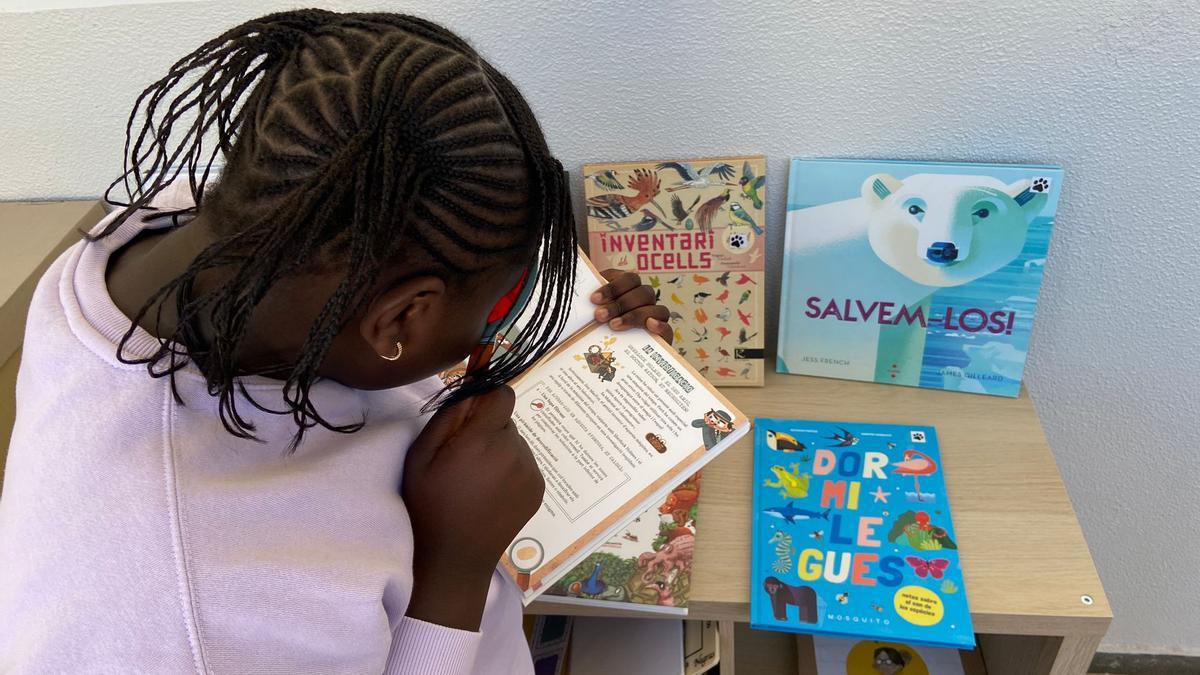 Una niña mira libros en el pasillo de una escuela catalana, este curso.