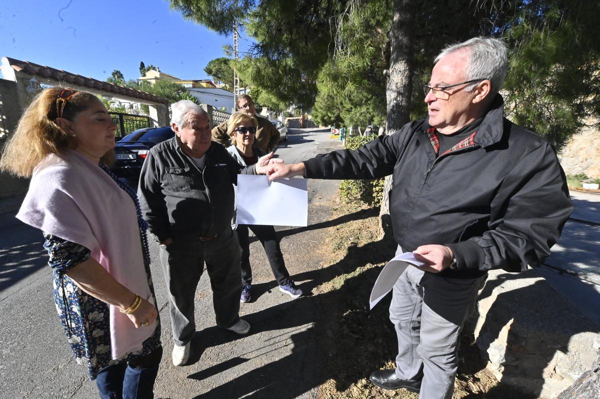 Un representante de la sociedad civil que gestiona el Pozo Peñarocha entrega un «comunicado urgente» a varios vecinos de la urbanización de Penyeta Roja de Castelló.