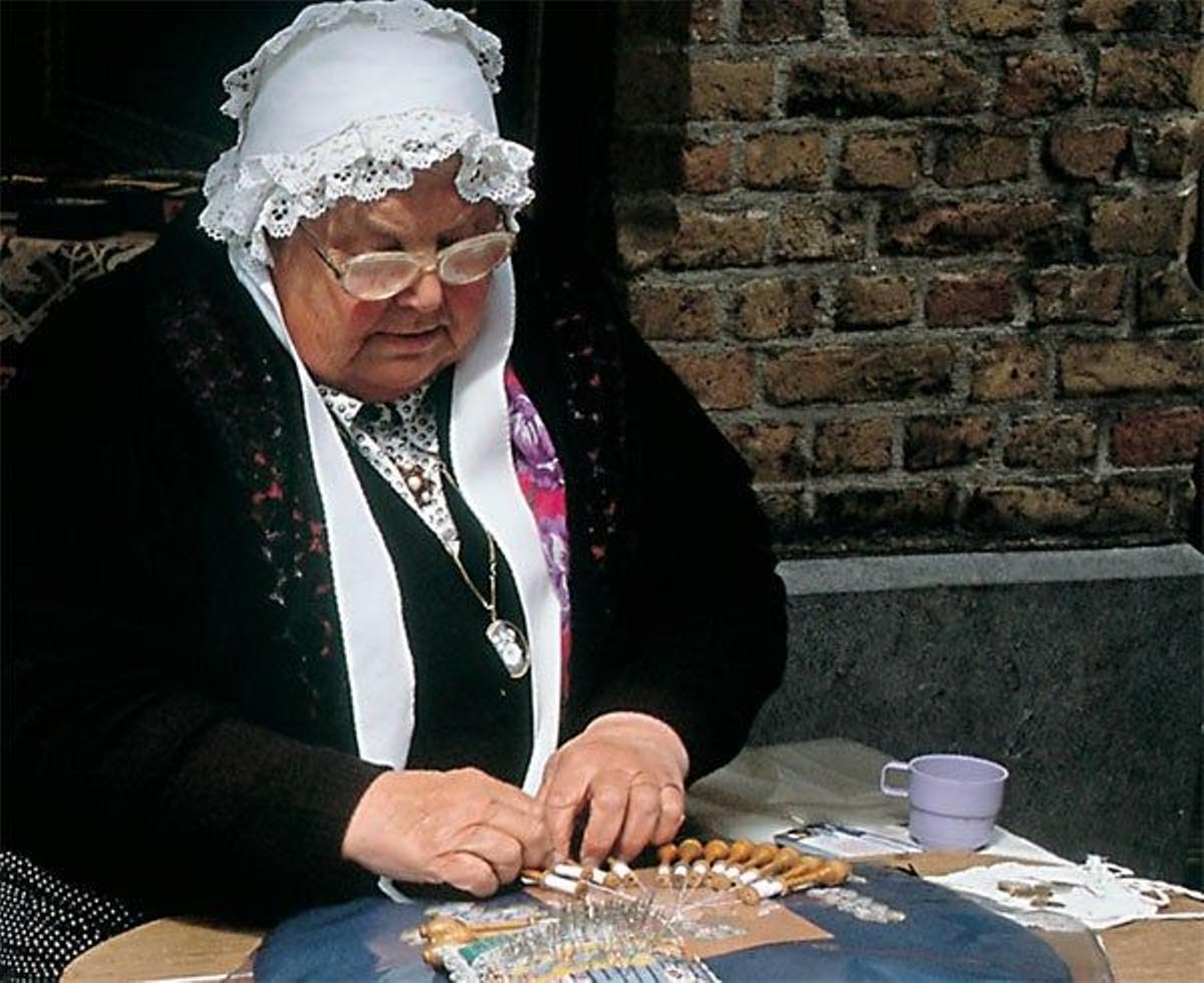 Una señora realiza encaje de bolillos.