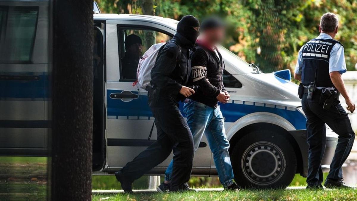 Agentes de policia trasladan a uno de los detenidos en la operación contra la ultraderecha en Alemania.