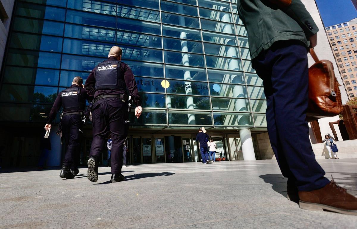 Dos agemtes de la Policía Nacional se dirigen a la entrada de Ciudad de la Justicia de València, sede de la Audiencia Provincial.