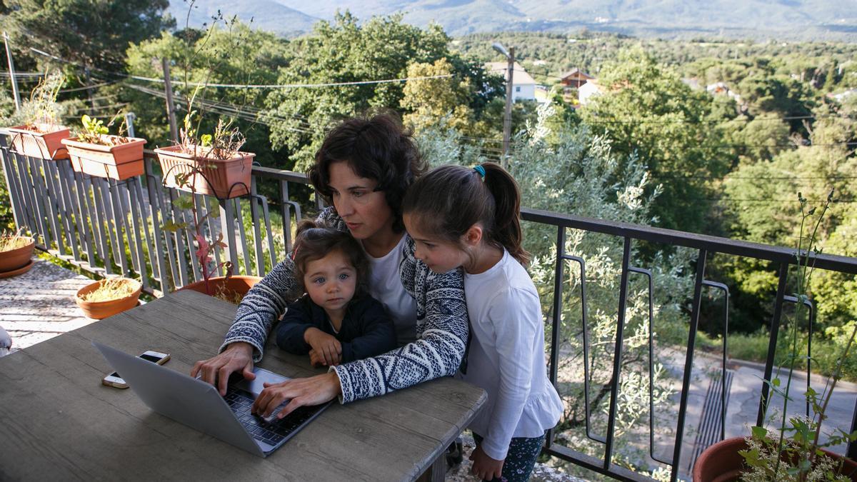 Una dona teletreballa mentre cuida les seves filles, en una imatge d’arxiu.