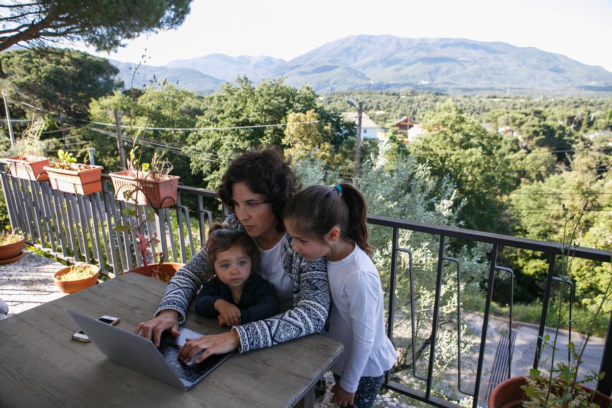 Una mujer teletrabaja mientras cuida a sus hijas, en una imagen de archivo.