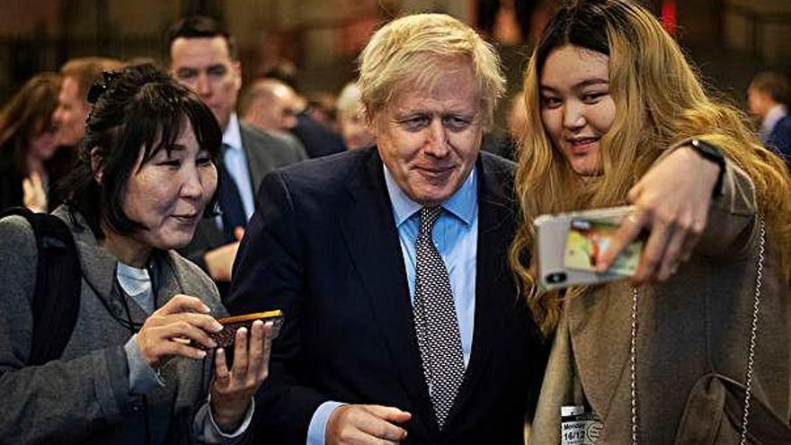 Boris Johnson fent-se fotos amb dues dones al Parlament.