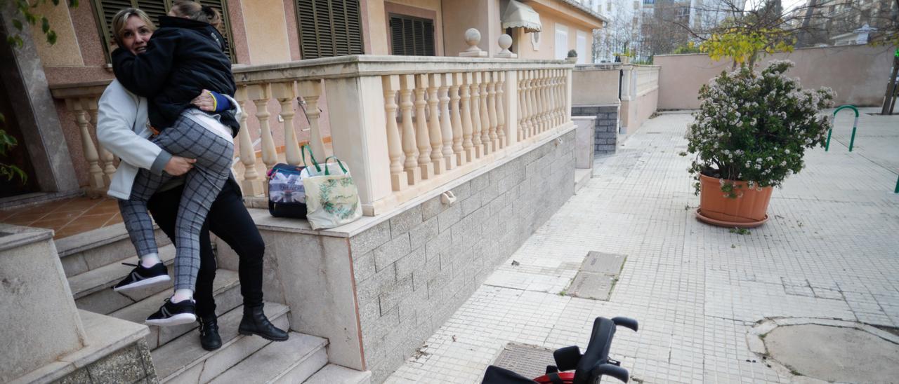 Teresa baja a su hija Alba por las escaleras para salir a la calle.