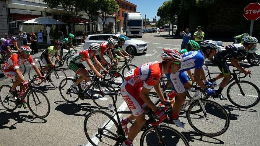 Una vuelta ciclista se incorpora a la Nacional 122 en Alcañices mientras los camiones esperan.