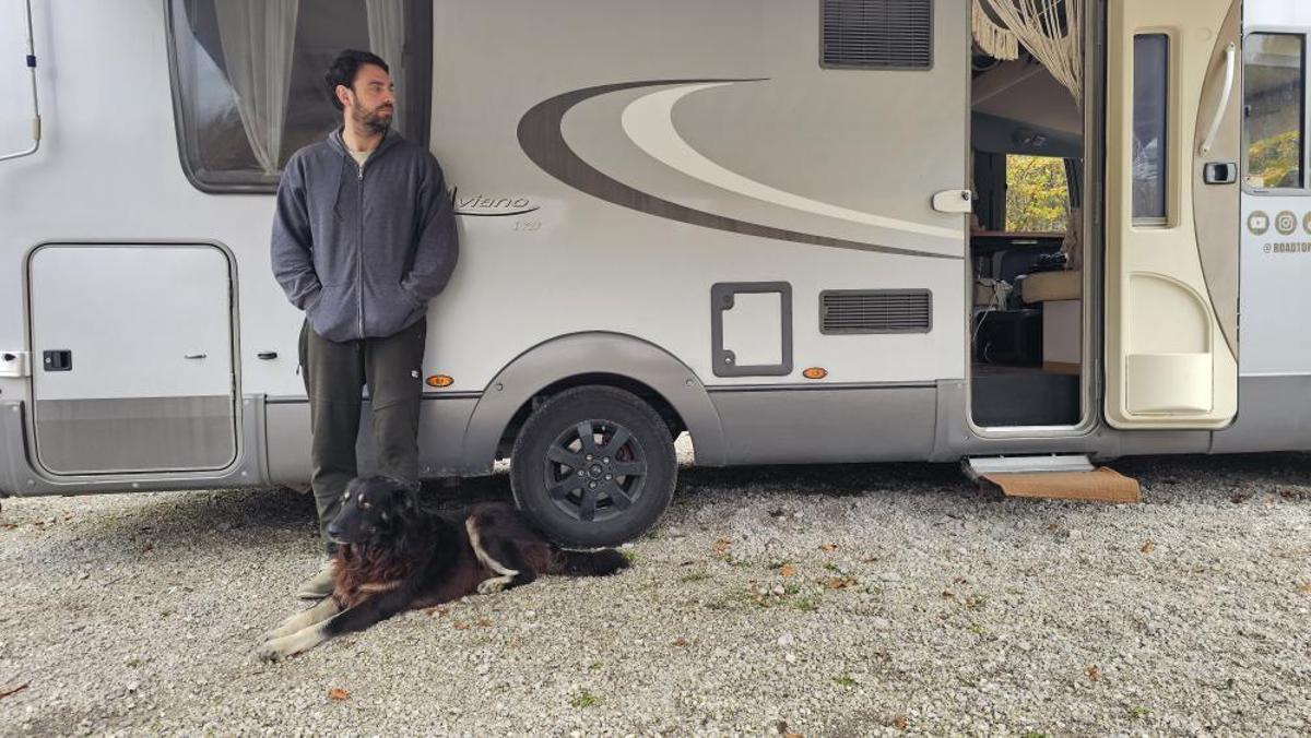 Pedro Acevedo, delante de su caravana, junto a uno de los perros que cuidan.