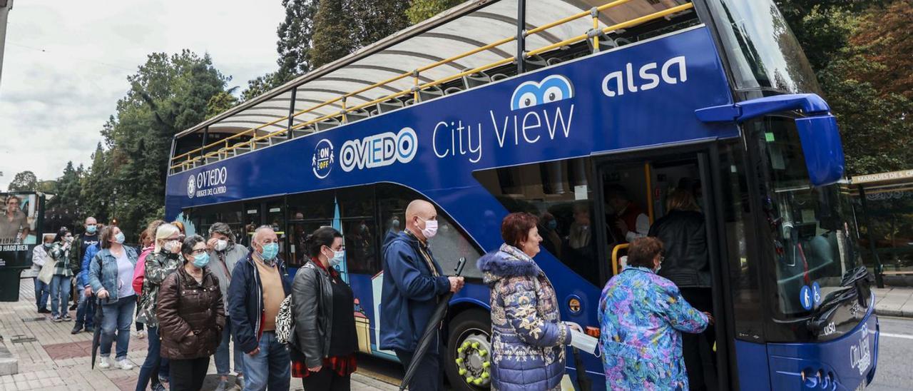 Personas haciendo cola para subirse al autobús turístico de Oviedo el pasado martes, con motivo del Día Mundial del Turismo. | Irma Collín