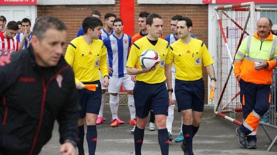 El portero del Izarra Aitor, vestido de naranja, tras el trío arbitral en Mareo. A la derecha, el técnico de ambulancia.