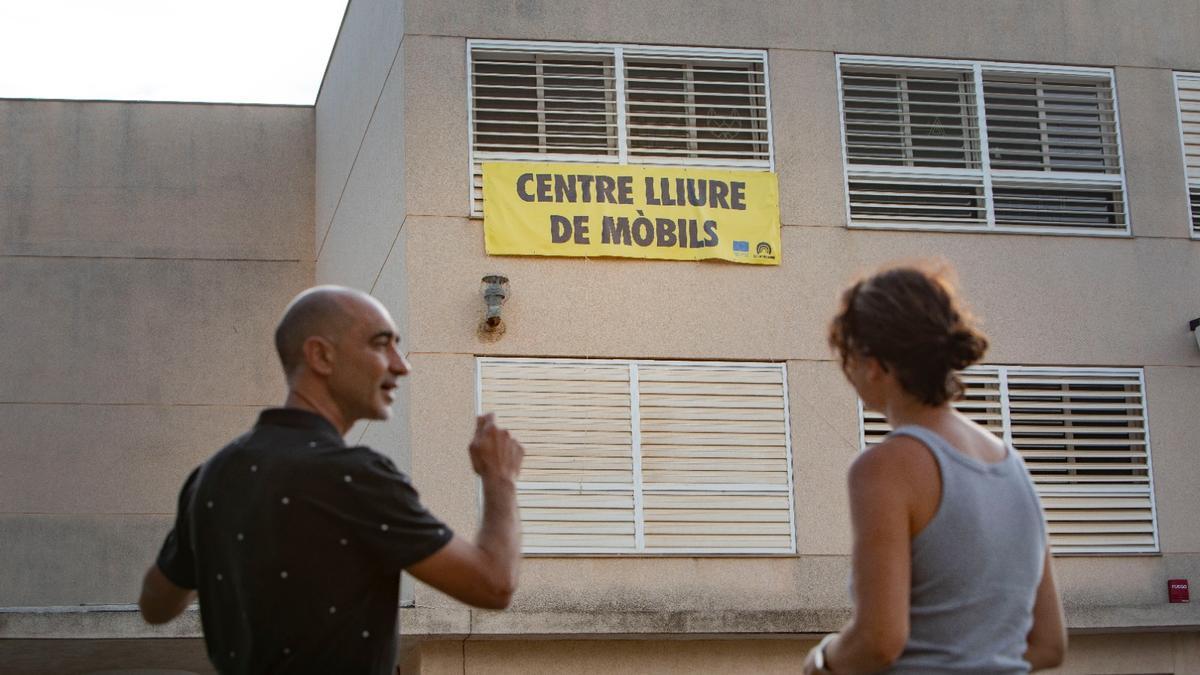 Dos profesores, ante la pancarta colocada en la entrada del centro.