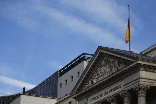 A Spanish flag flies at half-staff on top of Spain's Parliament as a police officer stands guard on a roof nearby, during the wake of Spain's former Prime Minister Suarez in Madrid