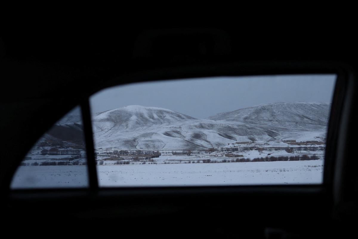 Colinas y campos cubiertos de nieve en Bamiyan (Afganistán), vistas desde el interior de un coche.