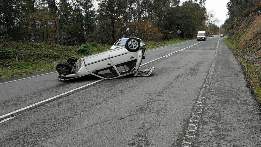 El coche acabó volcado en la calzada tras impactar con el talud del monte. // Gonzalo Núñez