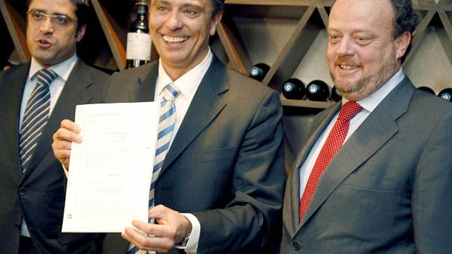 Fernando Sacristán, en medio de sus dos abogados, muestra la sentencia que condena al colegio. / efe