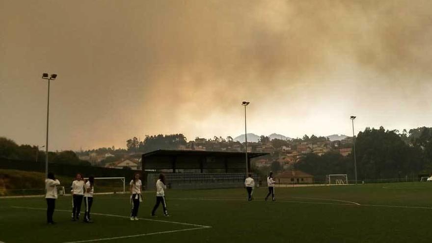 Las jugadoras sobre el campo de As Relfas, rodeadas de humo, ayer en Vigo.