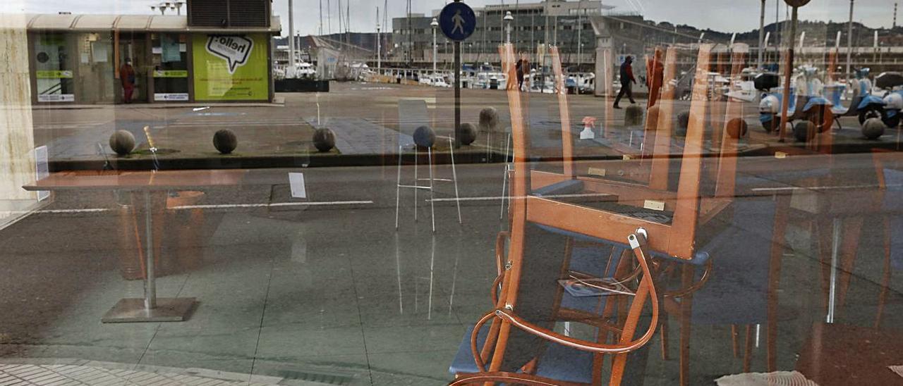 Sillas apiladas tras el cristal de un negocio hostelero de la ciudad cerrado.