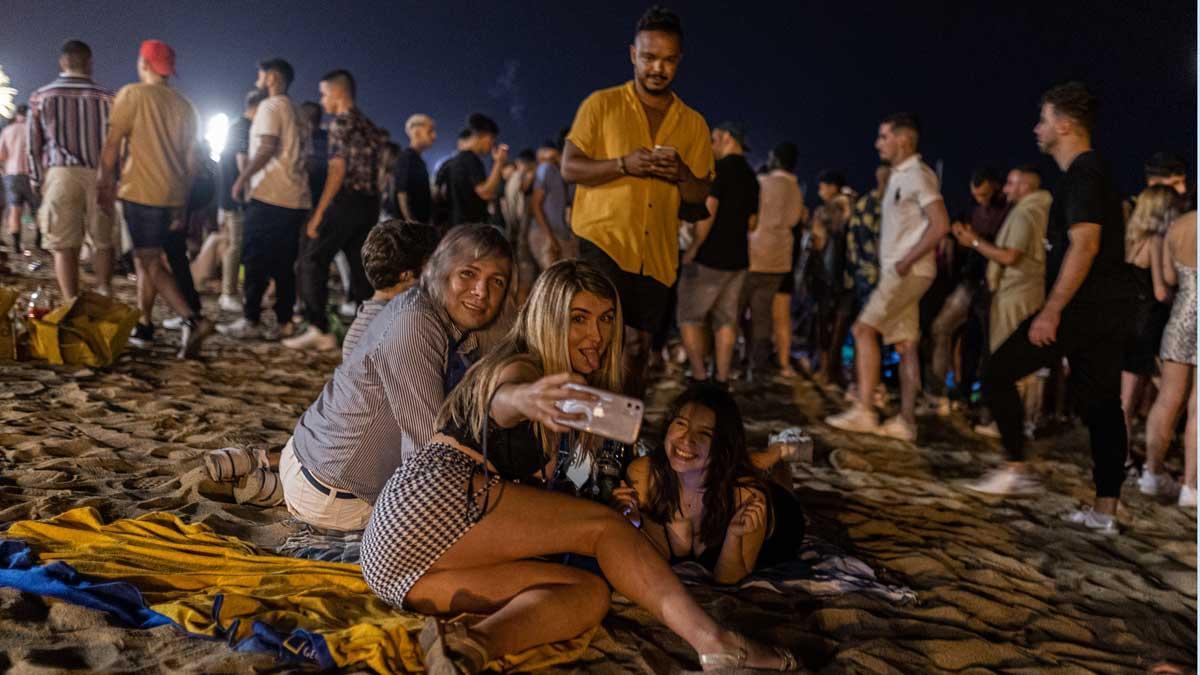 Unas chicas se hacen un selfi mientras están de fiesta en la playa de la Barceloneta, de madrugada