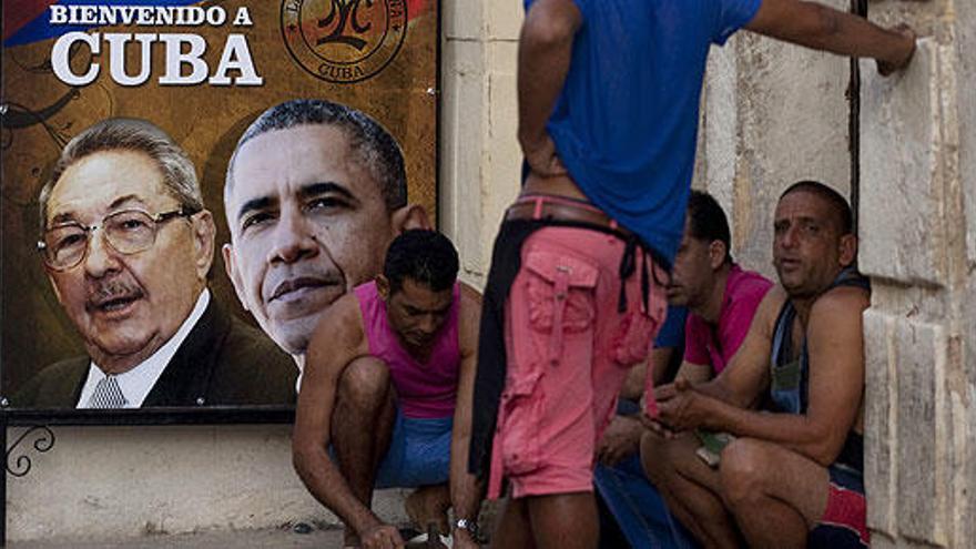 Cubanos ante un cartel de bienvenida a Obama.