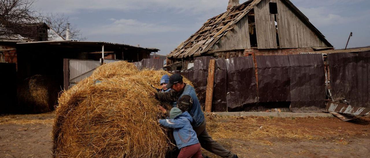 Un granger ucraïnès i els seus néts empenten un fardell de fenc als afores de Khàrkiv