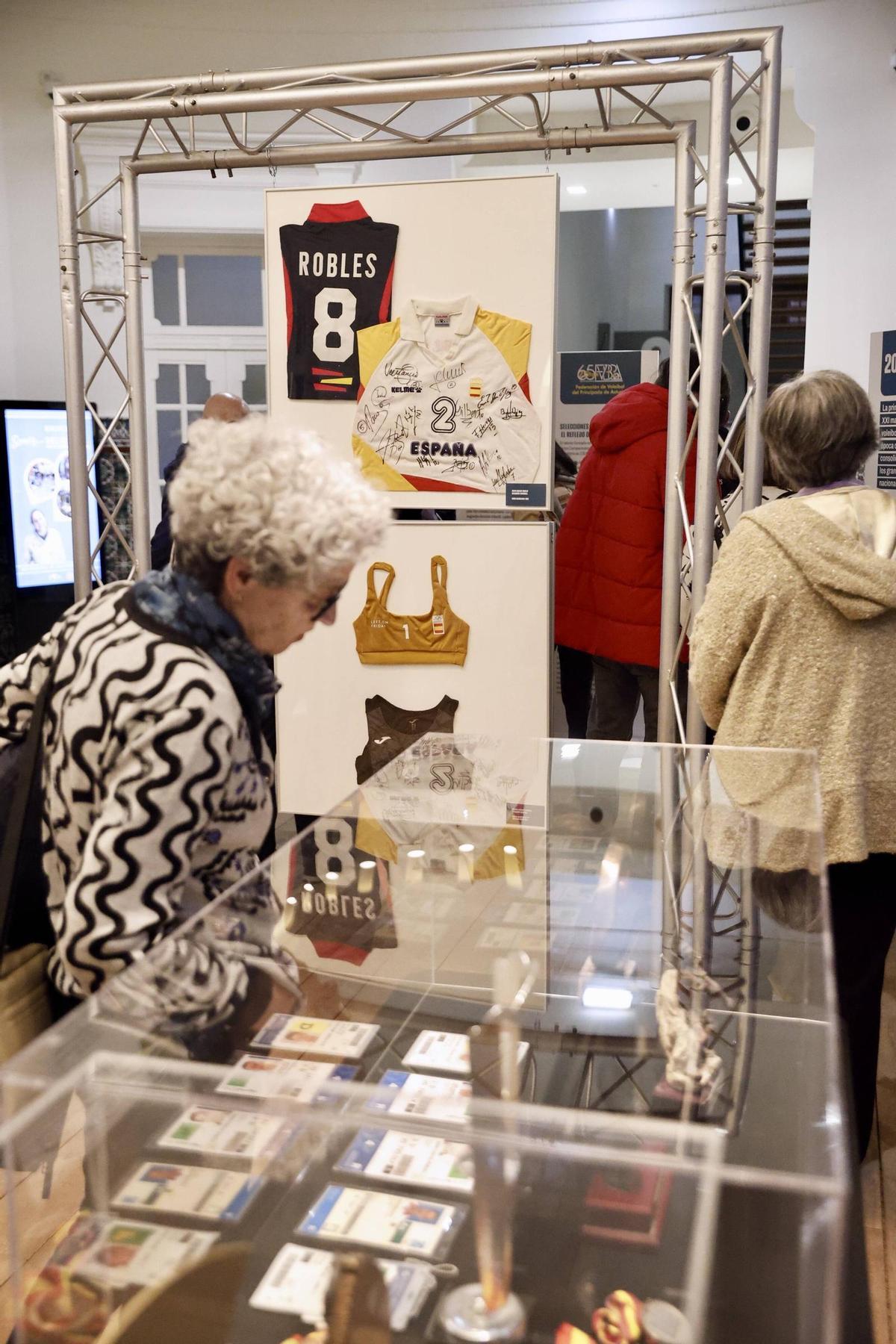 Visitantes observando la zona de vitrinas y paneles con trofeos, licencias y camisetas de los internacionales.