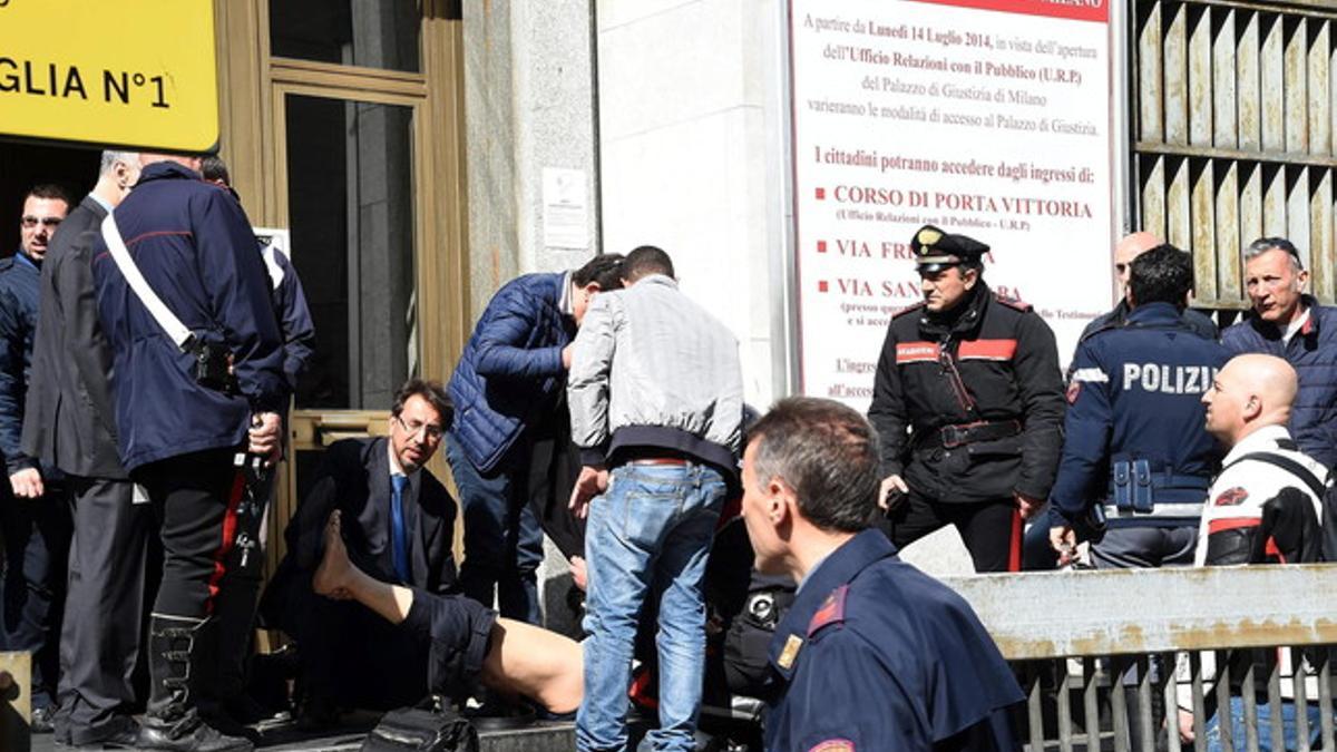 Policías y miembros de los servicios de rescate asisten a un herido a las puertas del Palacio de Justicia en Milán.