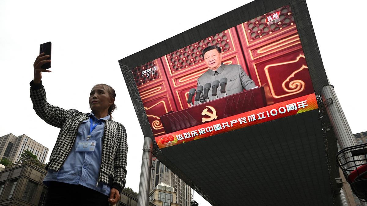 Una mujer se hace un 'selfie' con la alocución del presidente chino Xi Jinping de fondo.