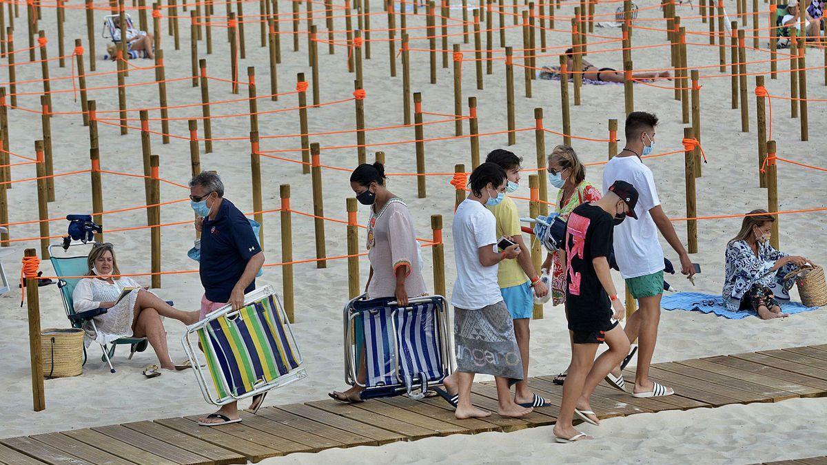 Bañistas en la pasarela de acceso a la playa de Silgar ayer por la tarde. Detrás de ellos, las estacas que dividen las parcelas.