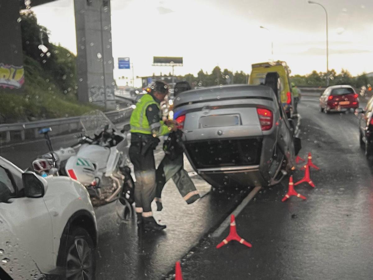 Un agente de la Guardia Civil al lado del vehículo volcado. Una herida leve al volcar su coche en Domaio bajo el puente de Rande. 26 mayo 2023.