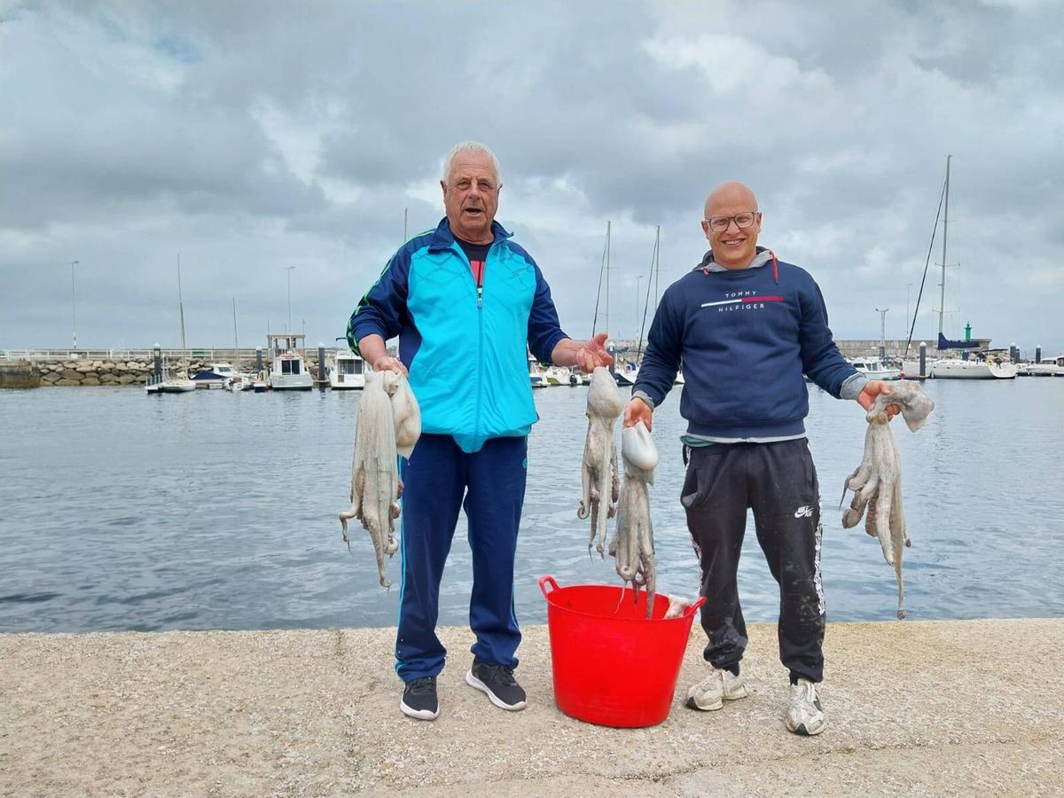Dos marineros de Bueu, este jueves, muestran las capturas de pulpo.