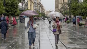 Personas caminan por el centro de Sevilla con paraguas cuando empiezan las primeras lluvias asociadas a la borrasca Bernard.