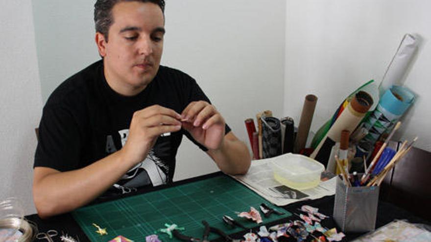 Diego Ante, en su taller y tres de sus piezas: broche gato negro, colgante carpa y pendientes pajarita.