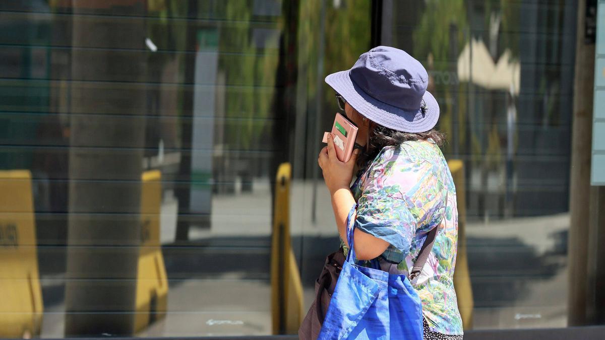 Una dona passeja amb gorro per protegir-se del sol, a Manresa