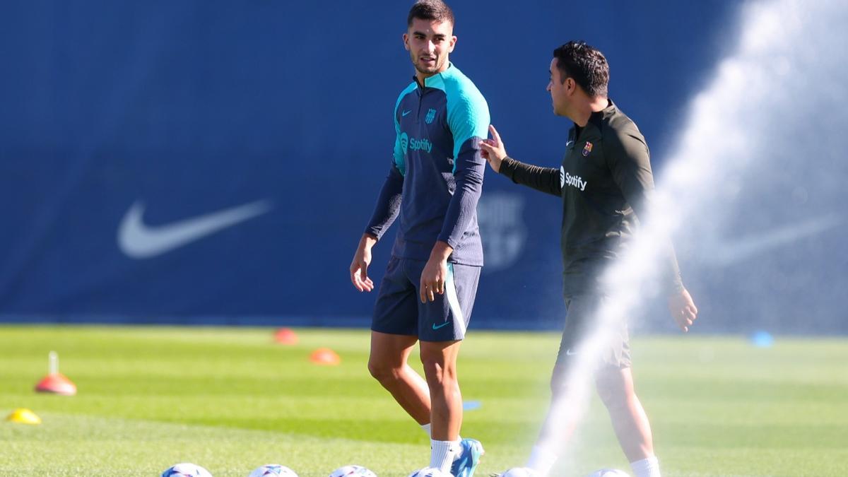 Ferran Torres y Xavi Hernández hablan en el inicio del entrenamiento.